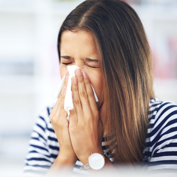 Woman with allergies sneezing into a tissue