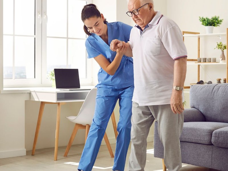 A nurse helping a senior man walk