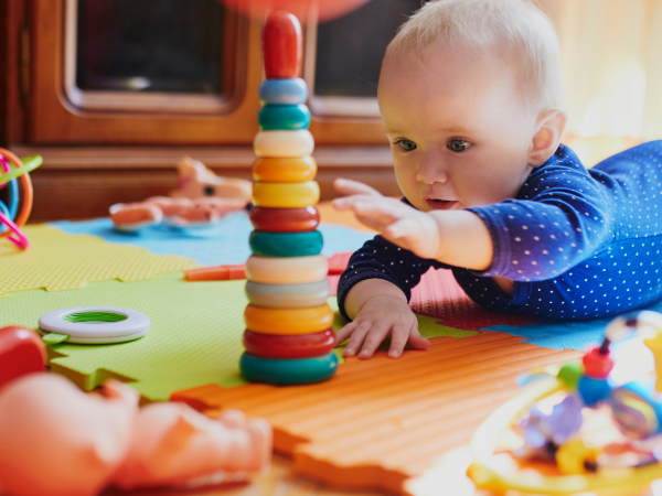 Baby playing with colorful toys on a foam tile floor