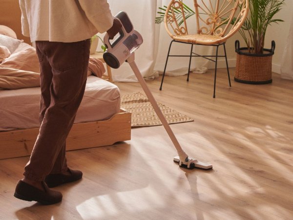 Vacuuming an LVP floor in a sunny bedroom